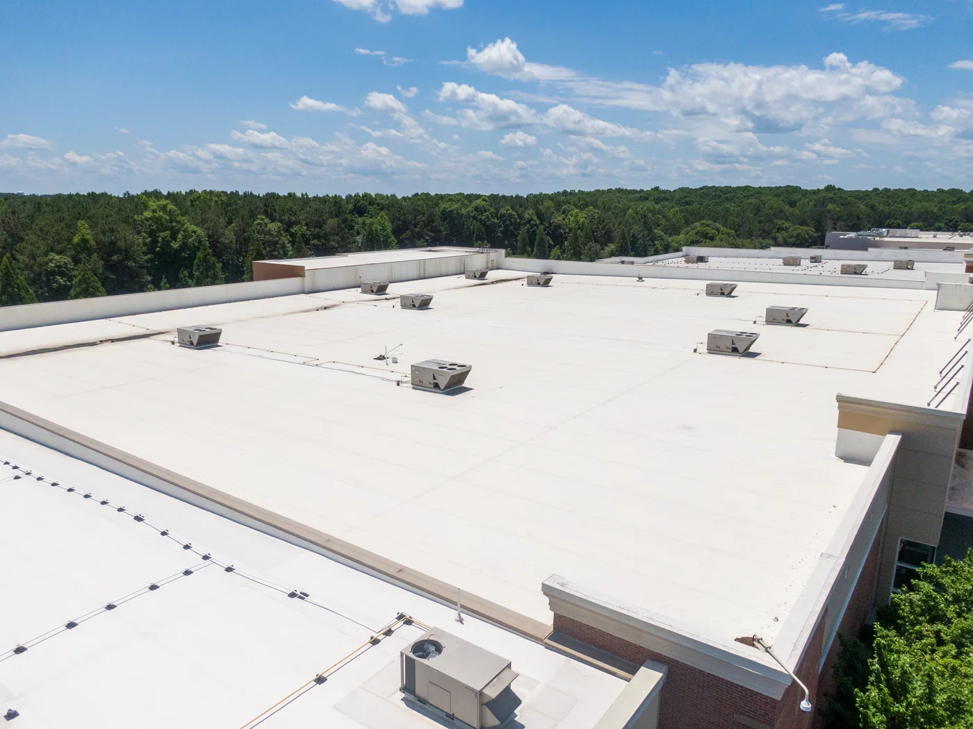 Aerial view of a large single-storey retail building with an expansive white membrane roof and rooftop HVAC units.