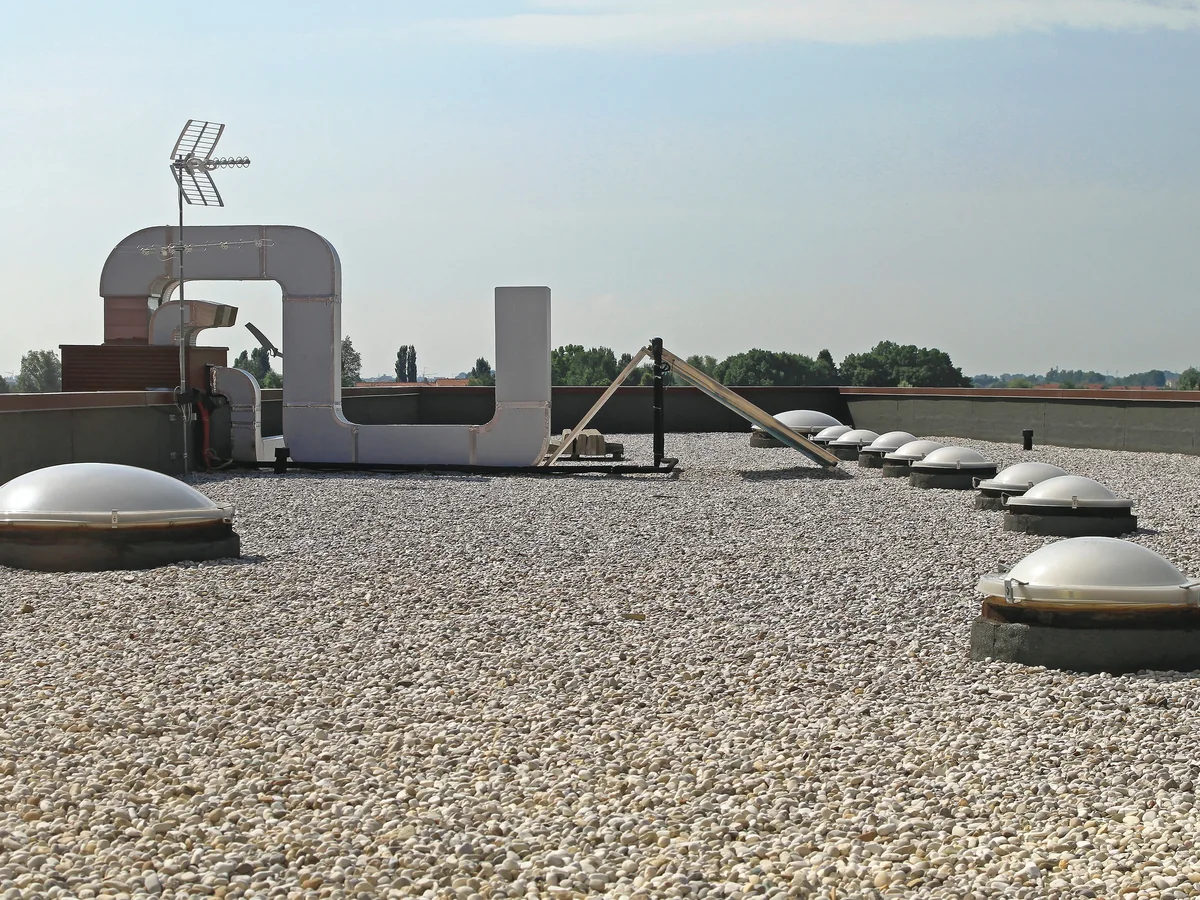 An older gravel-ballasted commercial roof with skylight domes, showing its age.
